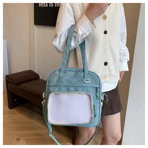 Detail of light blue-green ita bag with front transparent mesh pocket and crossbody strap