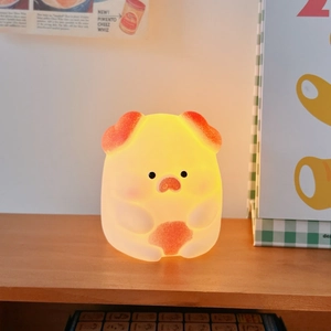 Macro detail of a pig-shaped night light glowing with warm light on a wooden shelf