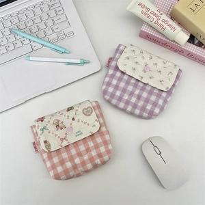 Close-up of quilted plaid pouches with floral details in a soft aesthetic desk setting