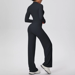 Detail view of high-waist wide-leg pants and slim-fit sports jacket in black matte fabric