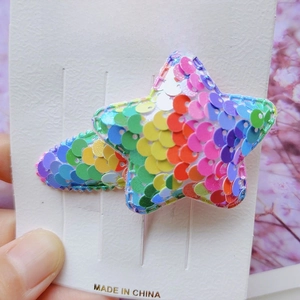 Close-up of glittery star hair clip with colorful rainbow sequins on display card