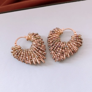 Vue détaillée de boucles d'oreilles cœur en fil d'or rose avec perles en verre colorées