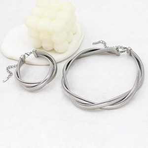 Detail of silver twisted snake chain necklace and bracelet set on marble surface