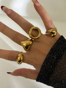 Close-up of four chunky gold geometric rings with high-polish mirror finish on a hand