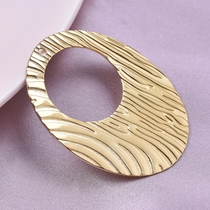 Macro detail of gold hammered oval pendant on purple fabric texture backdrop