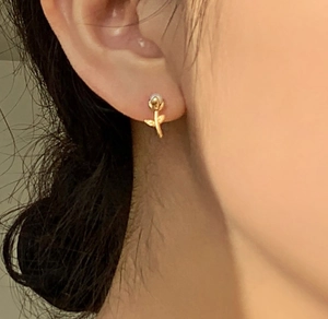 Vue macro de boucles d'oreilles rose dorées avec perle centrale et détail de feuille