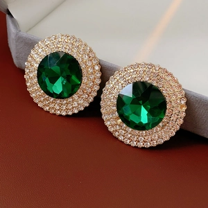 Close-up of luxury emerald green glass earrings with diamond halo on velvet tray