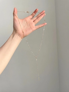 Close-up of gold Y-shaped tassel necklace with crystal accents and lobster clasp