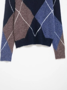 Close-up of argyle knit sweater detailing navy, brown and grey tones with wool texture
