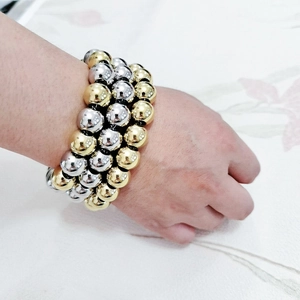 Detail of three-row metal beaded bracelet in gold and silver finish worn on wrist