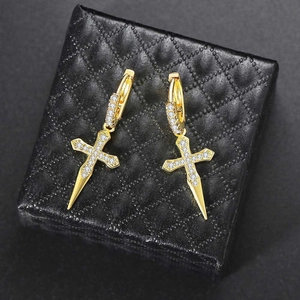 Macro shot of gold cross earrings with sparkling white cubic zirconia on black jewelry box