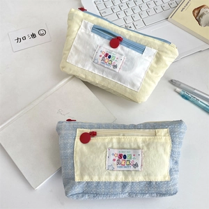 Close-up of cute canvas pencil case showing dual-compartment zipper and logo detail