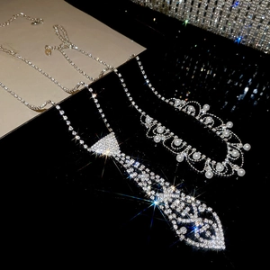 Detail of silver rhinestone tie necklace and pearl chain on a black background