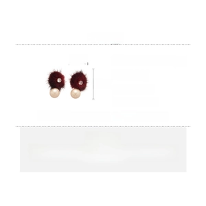 Detail view of red hairball earrings with shell pearls and sparkling cubic zirconia