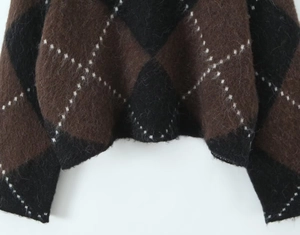Close-up of the plush knit texture and brown plaid argyle pattern on sweater hem
