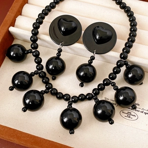 Close-up of black acrylic beaded necklace and heart-embossed earrings in a jewelry box