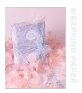 Detail of mermaid scale pattern wrapping paper with Happy Birthday text and pink feathers