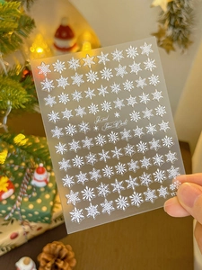 Detail view of 3D embossed white snowflake nail stickers with festive winter backdrop