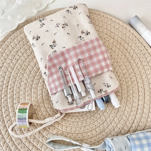 Detail of floral nurse pocket organizer with pink plaid pouch on a woven mat