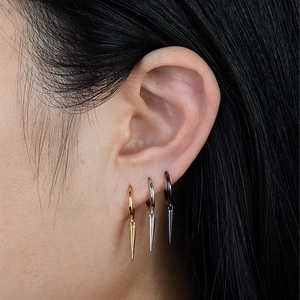 Close-up of model wearing gold silver and black hoop earrings with spike charms