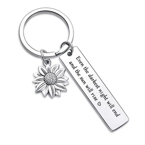 Detailed close-up of sunflower keychain with engraved inspirational quote on silver tag