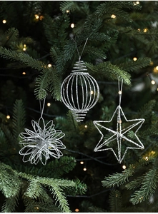 Close-up of silver glitter star and lantern ornaments on a green Christmas tree