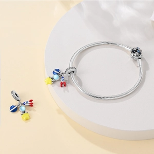 Detail view of silver rocket and planet charms on a snake chain bracelet with enamel finish