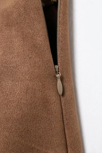 Close-up of invisible side zipper on brown velvet skirt suit with detailed fabric texture