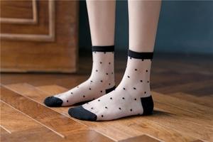 Detail of white transparent sheer socks with black polka dots and reinforced heel