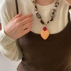 Close-up of leopard print fabric necklace featuring a large orange heart pendant for women