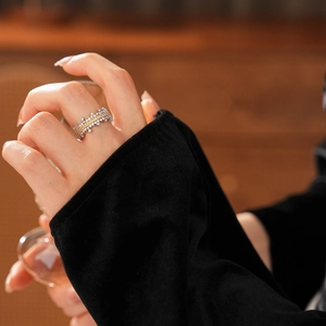 Close-up of a zircon-encrusted crown ring in gold and silver, worn by a hand holding a glass