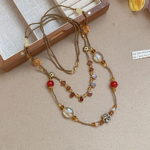 Detailed close-up of retro bohemian beaded necklace with ceramic floral and amber glass beads
