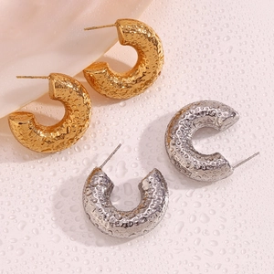 Detail of C-shaped earrings with hammered metal texture in gold and silver plating