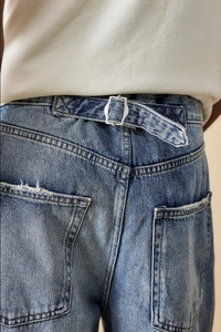 Detail of adjustable metal buckle and vintage washed denim texture on wide-leg jeans
