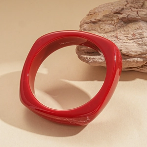 Detailed view of polished red resin square geometric bangle with smooth rounded edges