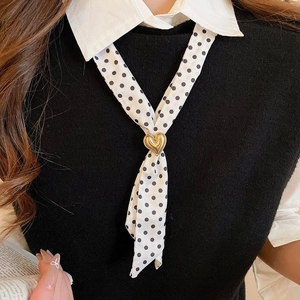 Close-up of black and white polka dot silk scarf necklace with a gold heart pendant charm