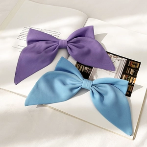 Detail view of large purple and blue satin bow hair clips on a magazine background