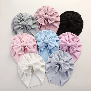Collection of infant turban hats with bows arranged in a heart shape on a white background
