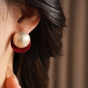 Detailed close-up of a vintage plush velvet earring with a white pearl on a model