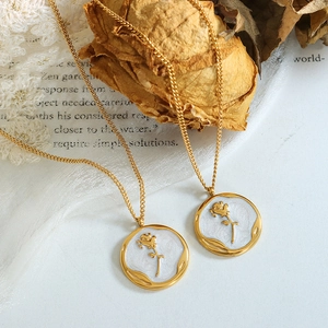 Vintage gold necklaces with rose relief charms and white enamel on aesthetic lace background
