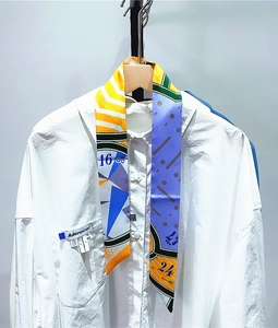 Detail of colorful twilly silk scarf tied on shirt collar showing geometric patterns