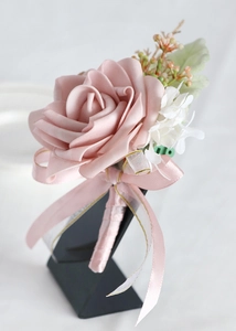 Detailed view of dusty pink PE rose boutonniere with satin ribbon and floral accents