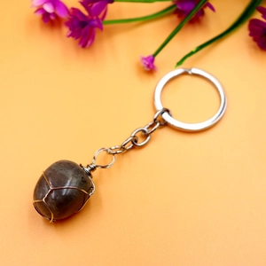 Macro shot of dark oval natural stone pendant wrapped in copper wire on a keychain