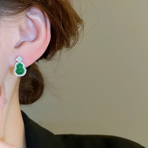 Close-up of a model wearing a green zircon gourd stud earring with silver setting