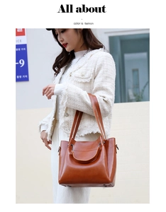 Close-up of caramel brown leather tote bag held by a model in a white jacket