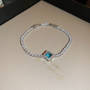 Detailed shot of sky blue four-leaf clover bracelet with zircon pavé setting on white box