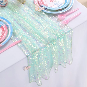 Detail of mint green sequin table runner with shimmering mermaid scales on soft mesh fabric