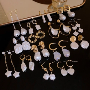 Macro view of baroque pearl and geometric gold star earrings on a luxury display tray