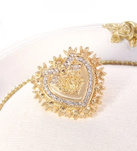 Detailed macro of gold heart brooch featuring intricate white crystal pavé and baroque relief
