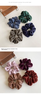 Detailed view of eight assorted color fabric scrunchies with elegant textured material